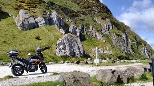 Suzuki Vstrom motorcycle parked with large rocks in background along the coast