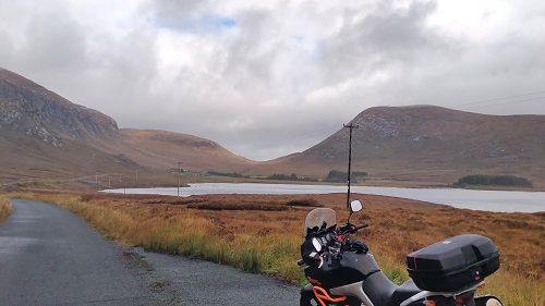 Suzuki Vstrom motorcycle in foreground with small lake and donegal hills in background