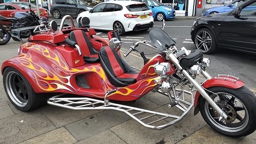 Red trike with flames painted on side parked on the pavement