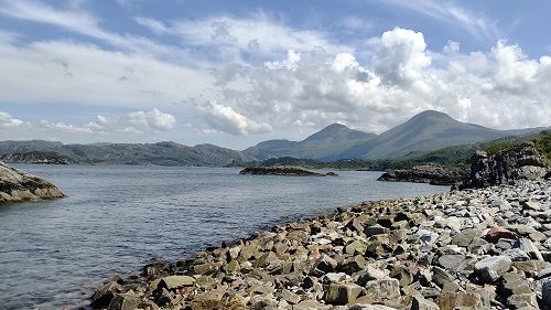 A lake in scotland with mountains on the other side in background