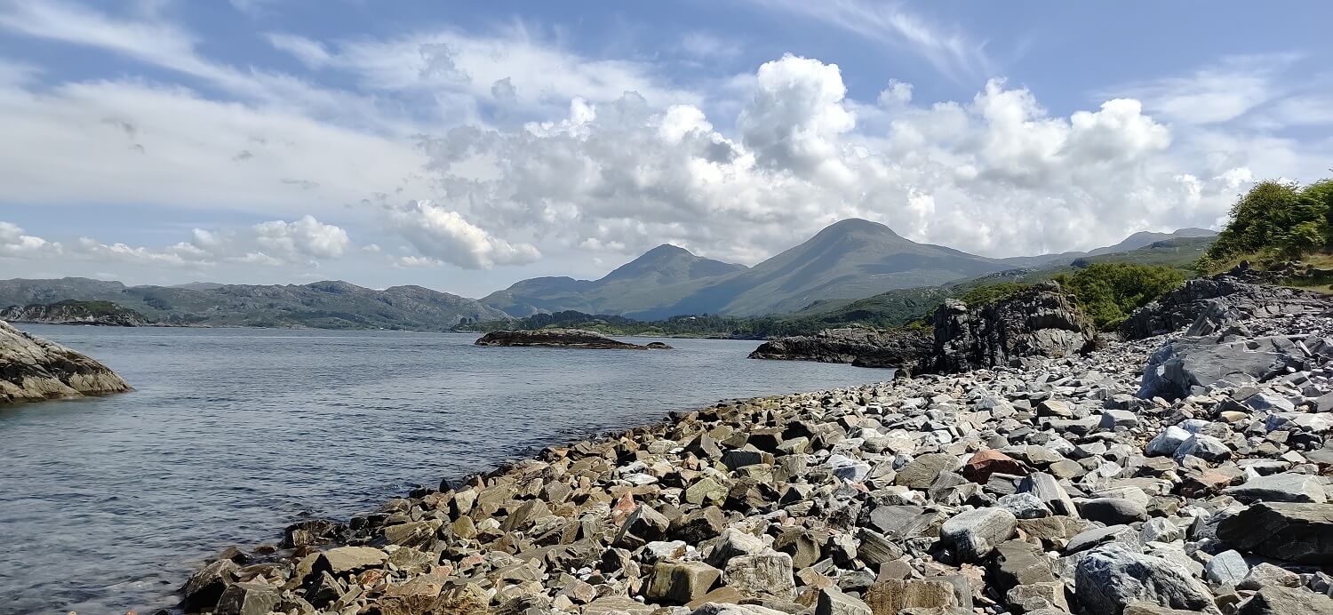 rocky shore along a loch near Fort William, Scotland with mountains in background