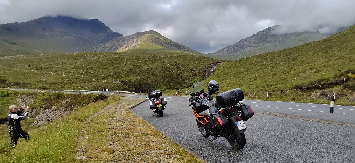 Two motorcycles parked on roadside in the highlands with mountains in background