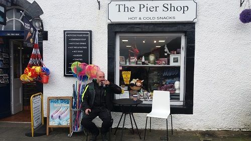 Taco sitting at a table outside the Pier Shop drinking coffee