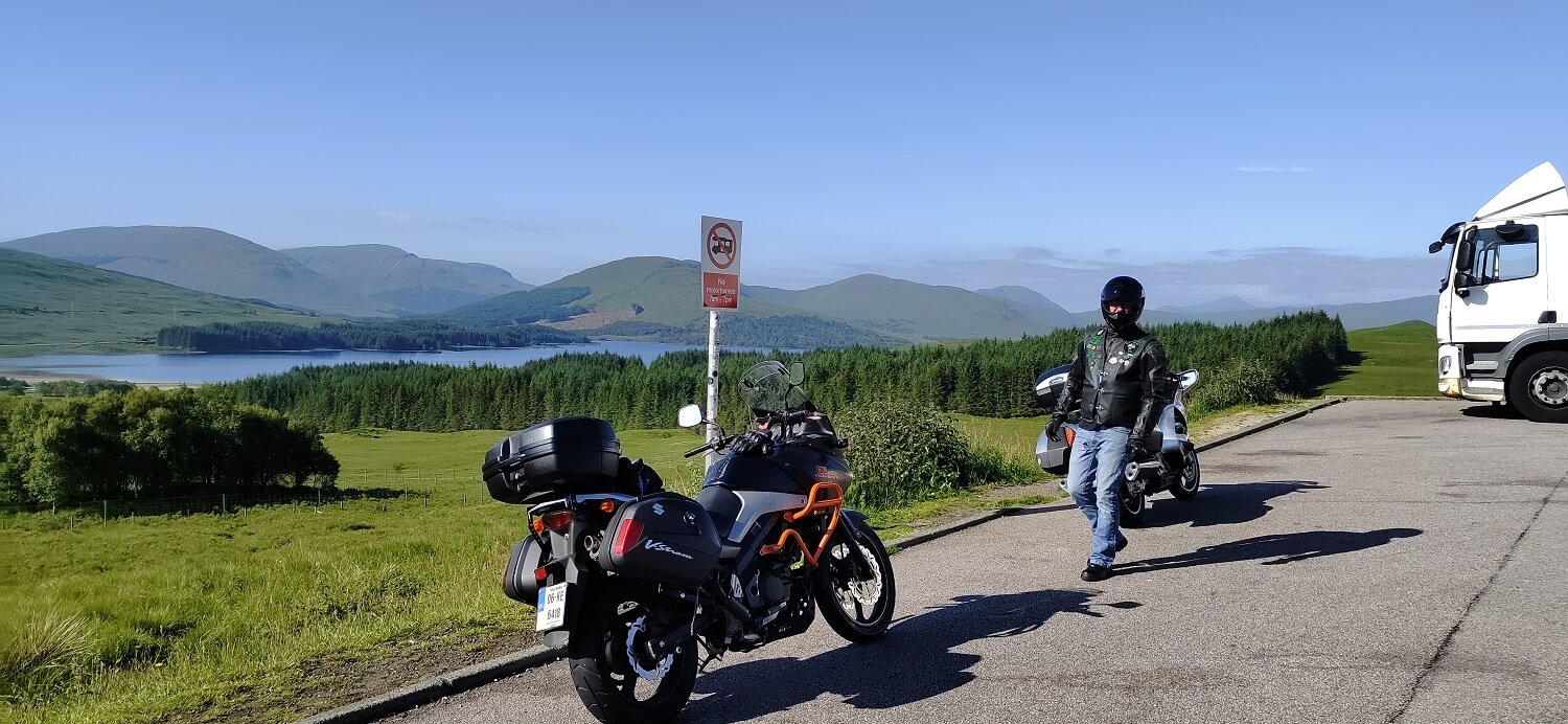 Two motorcycles parked on roadside in the highlands with mountains in background